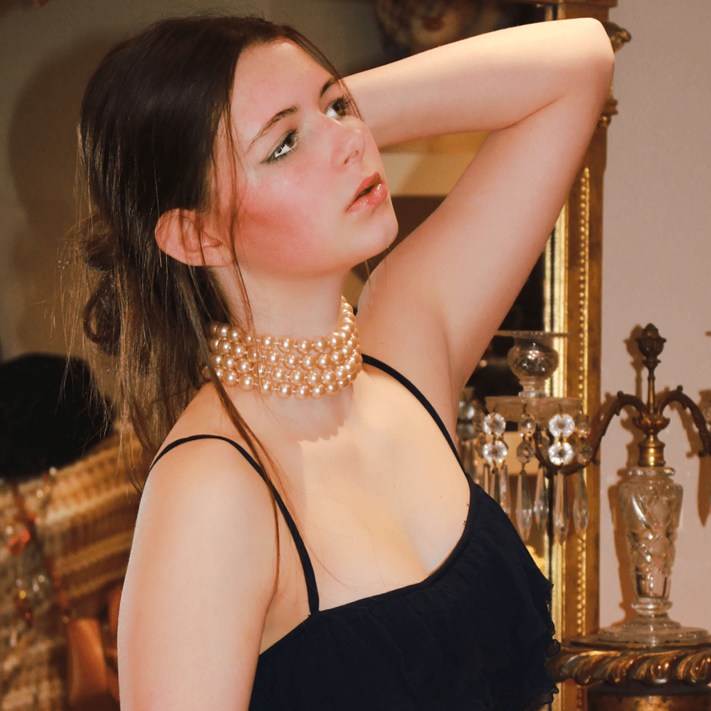 A Constantine Rex model wearing a vintage pearl necklace consisting of four layers of pearls. She's looking up with her arm behind her head, showing off the jewellery beautifully.