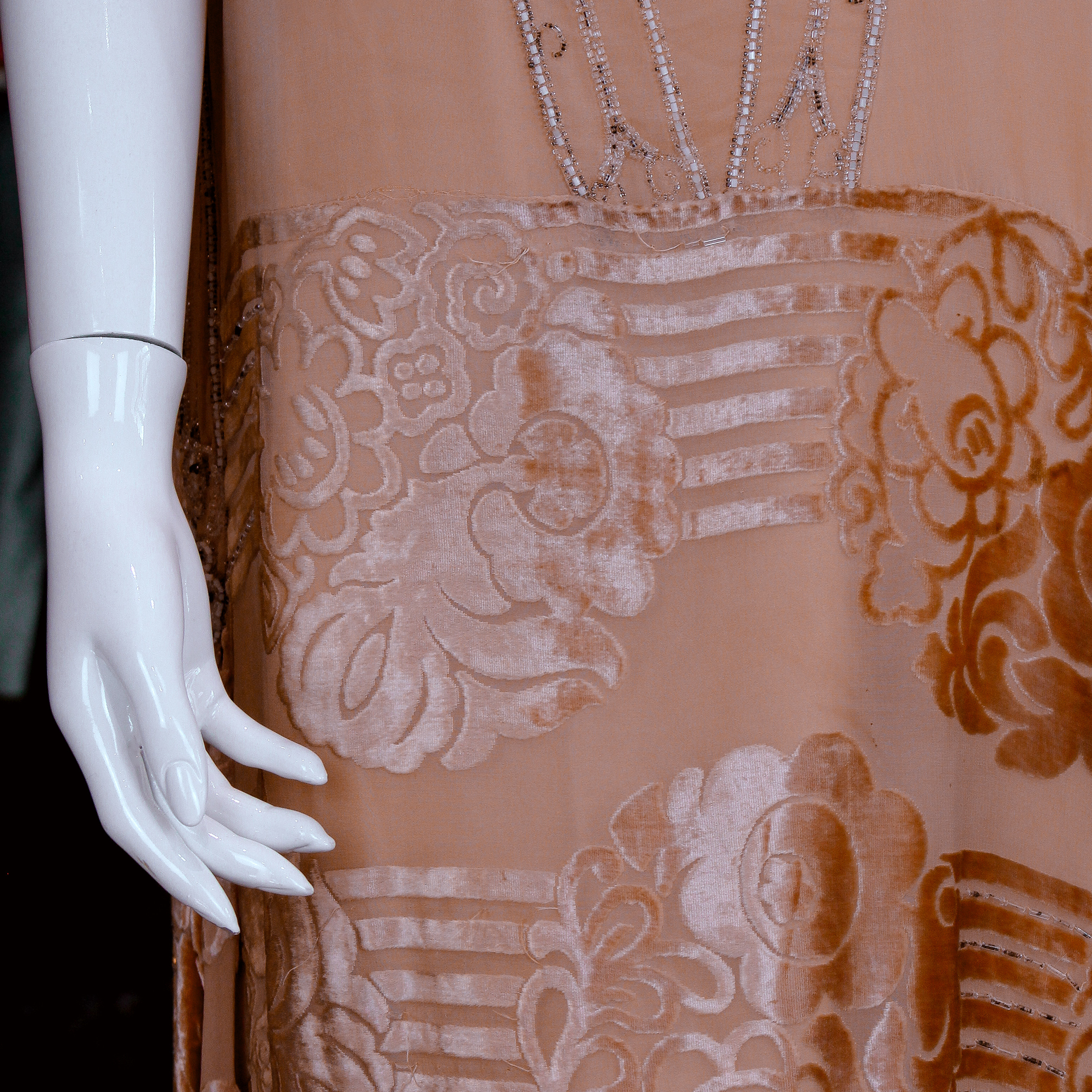 Mannequin wearing a vintage peach flapper dress with bead detailing.