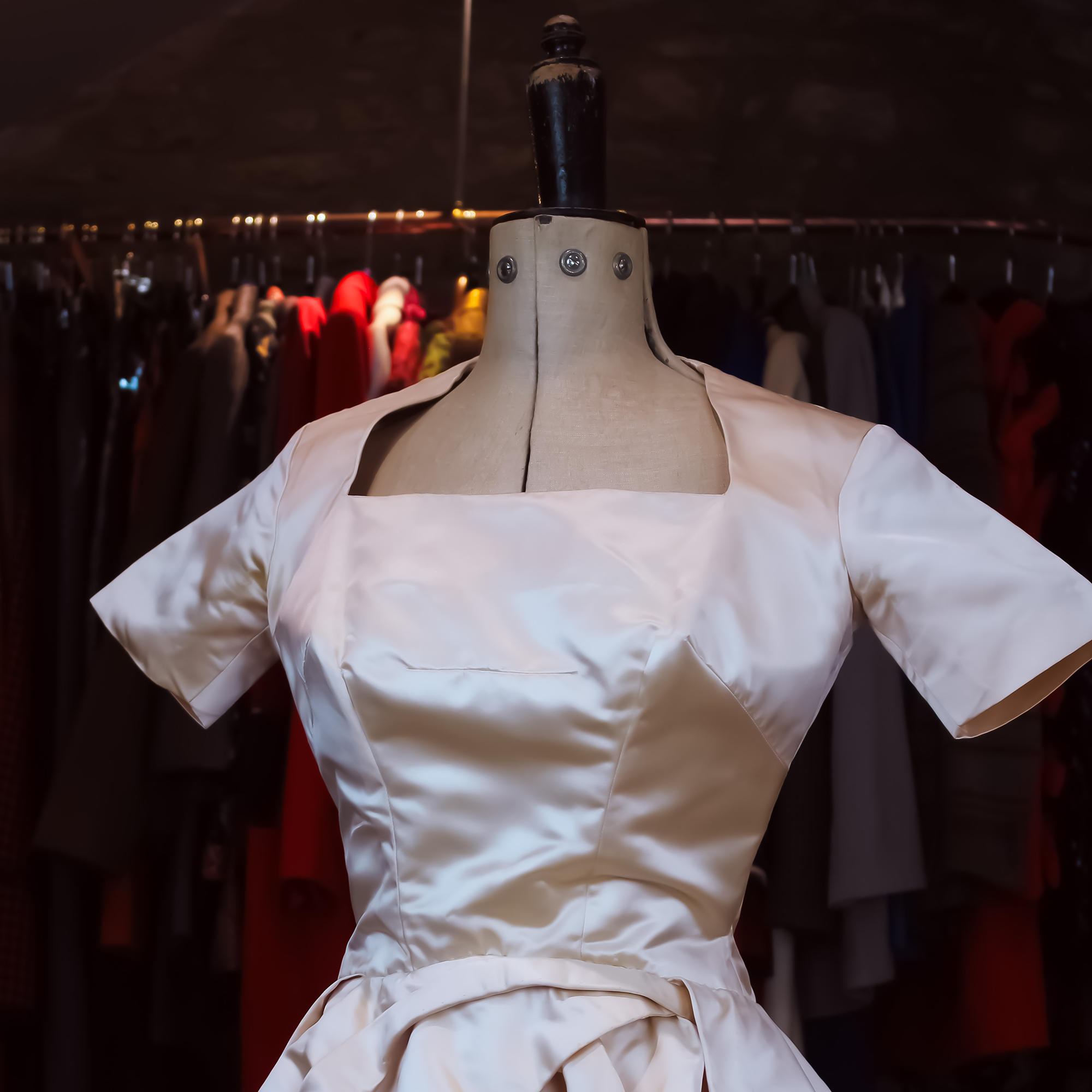 Vintage designer wedding dress in front of a wall of luxury clothing in Constantine Rex Ltd boutique.